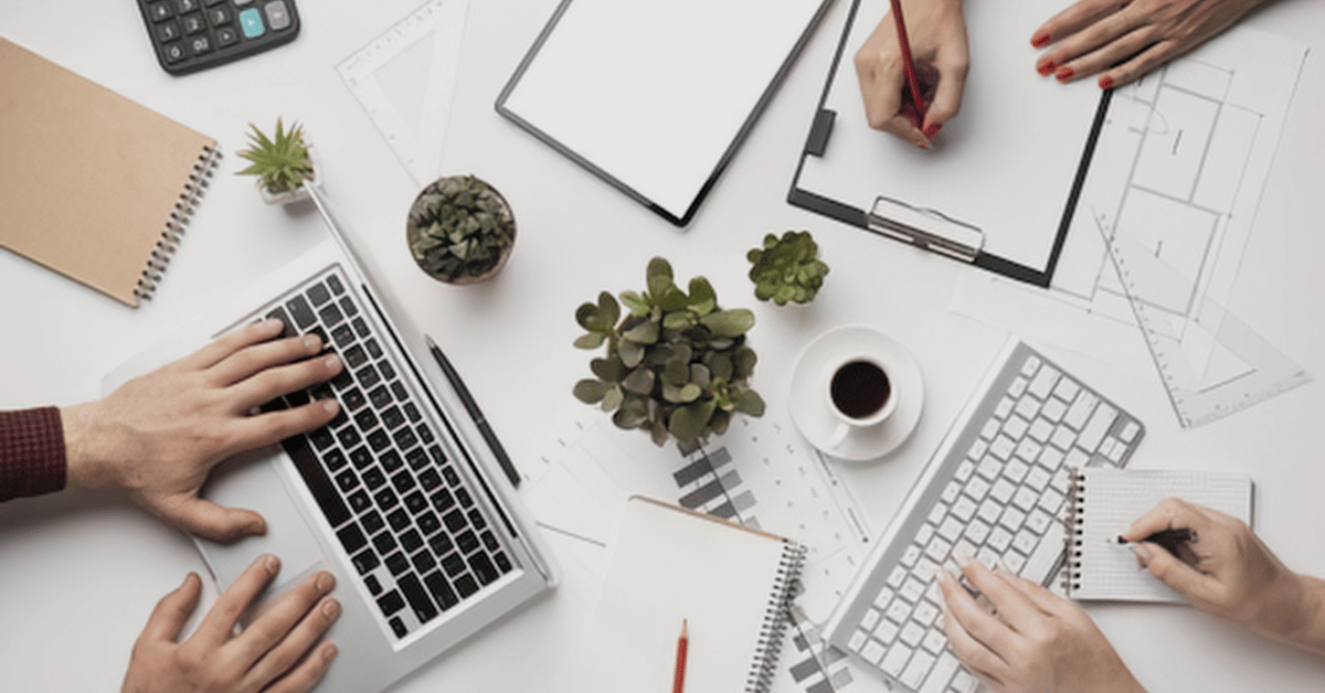 Overhead view of a team working together at a desk with a laptop, notebooks, and shared materials