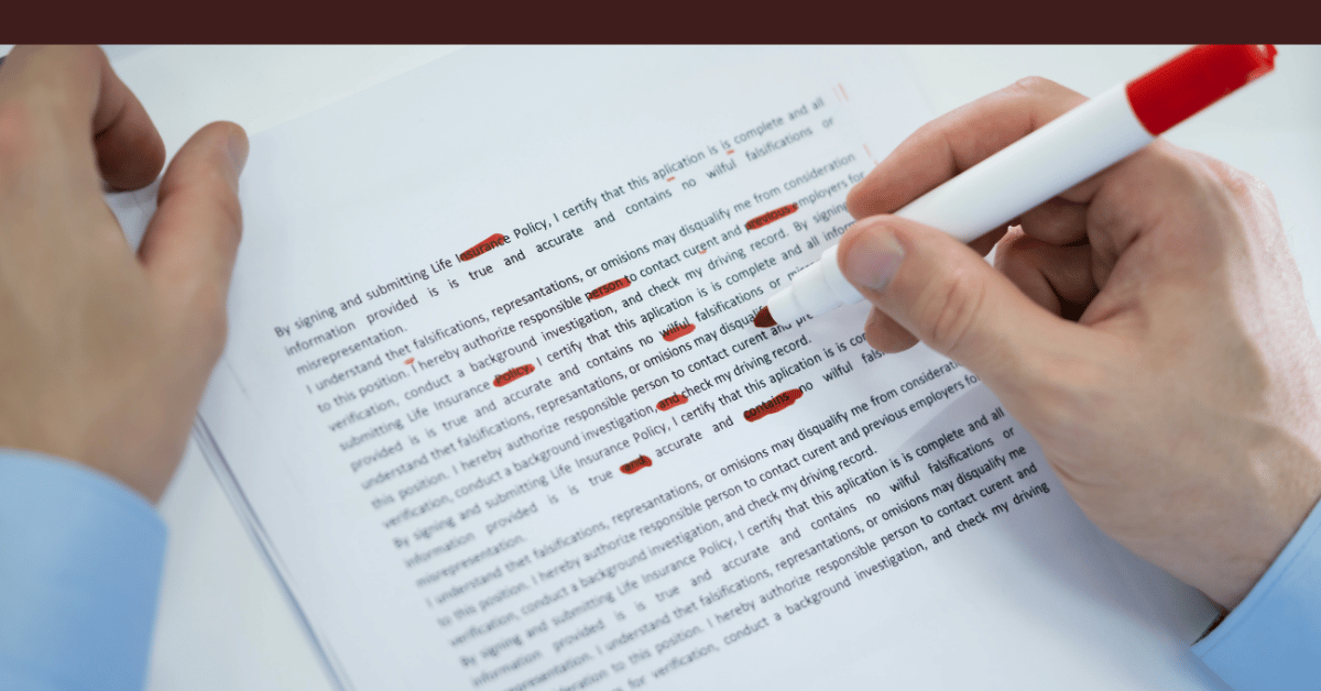 Close-up of hands editing a printed document with a red pen and multiple corrections.