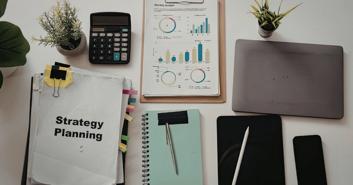Overhead view of a desk with a laptop, notebook, and documents arranged for strategy planning