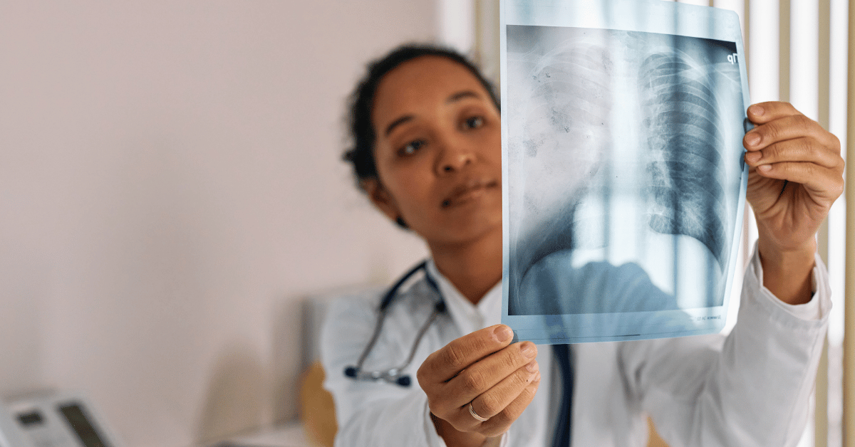 A doctor studies a chest X-ray, illustrating the process of diagnosing hidden problems before recommending a solution.